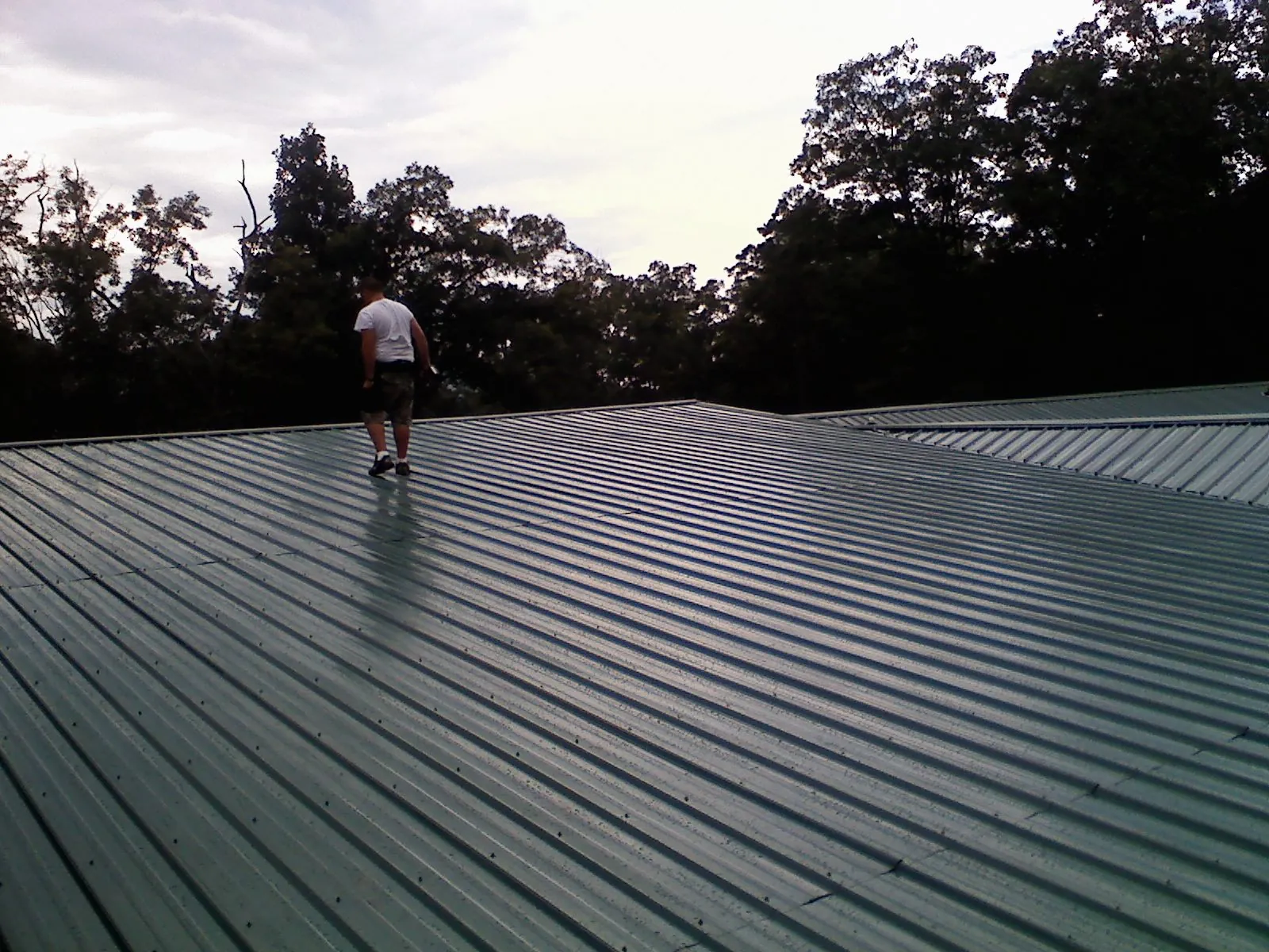 Roofer walking a wide expanse of new green metal roofing in Fairfield