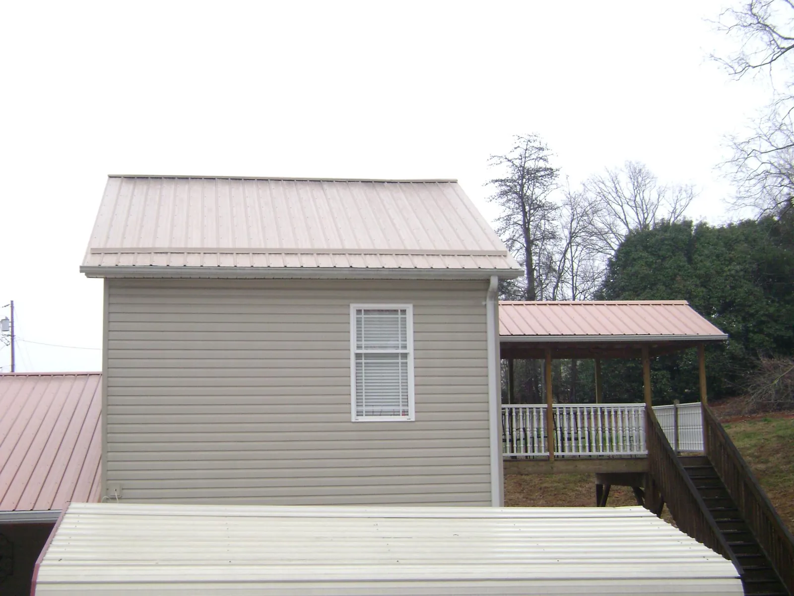 Tan metal roofs on a two story addition and attached porch, from a Roof Replacement job in Fairfield