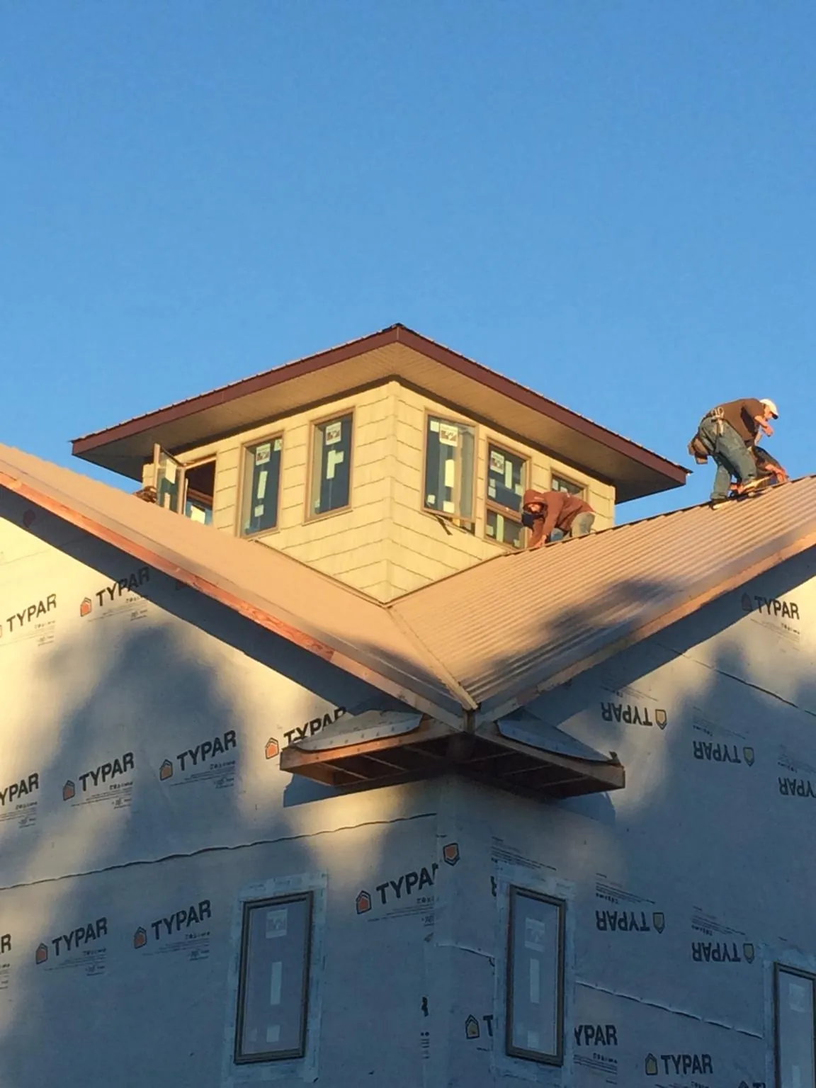 Roofers working around a rooftop cupola on a new metal roof at sunset — Roof Waterproofing in Fairfield by Roofing Brothers